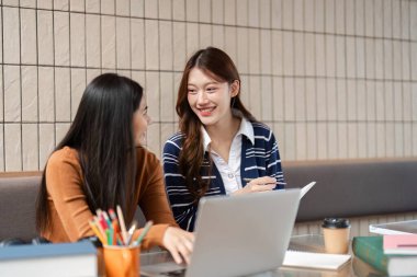 Kalabalık bir kafede, iki arkadaş görevleri üzerinde özenle çalışır, bilgi ve ipuçlarını paylaşır, çalışma zamanını eğlenceli ve verimli kılar..