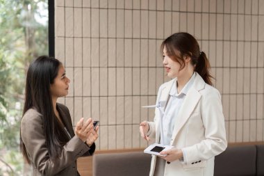 İki kadın, modern bir çalışma alanında sürdürülebilir enerji çözümlerinin önemi hakkında profesyonel bir diyalog içindedir..