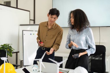 Teknoloji ve modeller kullanılarak yenilenebilir enerji çözümleri üzerine fikir alışverişinde bulunan iki profesyonel, sürdürülebilirlikteki takım çalışmasının örneğini sunuyor.
