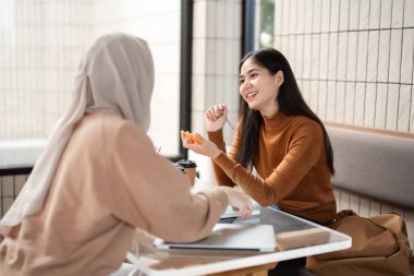 Gündelik bir kafe ortamında, iki arkadaş bir proje üzerinde işbirliği yaparak yaratıcılıklarını ve içgörülerini birleştirirken kahvenin tadını çıkarırlar..