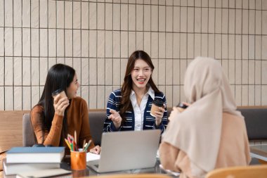 Üç kolej arkadaşı şık bir kafede buluşup, fikirlerini paylaşıyor ve kahve eşliğinde çalışmalarında işbirliği yaparak, canlı ve destekleyici bir atmosfer yaratıyorlar..
