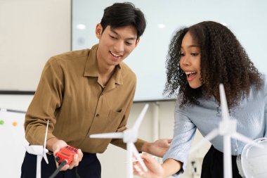 Sürdürülebilir enerji odaklı bir proje üzerinde çalışan iki tutkulu birey, rüzgar türbini modellerini coşku ve yenilikle inceliyor.