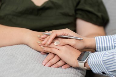 Şefkatli bir psikiyatrist, terapi sırasında sıcaklığın ve bağlantının önemini gösteren sıkıntılı bir müşterinin elini tutar..