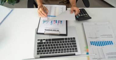 İşine odaklanan bir profesyonel, gösterişli bir ofis ortamında etkin belge uygulamaları sağlayarak, mali grafikleri ve istatistikleri incelemekle meşgul..