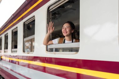 Treni ayrılırken, el sallıyor. Mutlulukla dolu ve yolculuk için macera dolu..