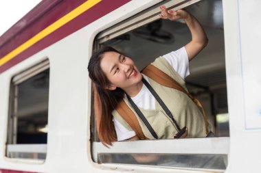 Neşeli bir ifadeyle, rüzgarın saçlarını okşamasından zevk alıyor. Pencereden dışarı bakıyor, seyahat macerasını kucaklıyor..