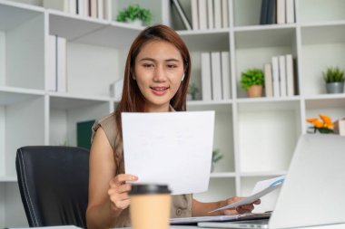 Kadın, bitkiler ve organizasyonel unsurlarla dolu çağdaş bir çalışma alanında üretkenliğe olan bağlılığını yansıtan önemli evrakları dikkatle inceliyor..