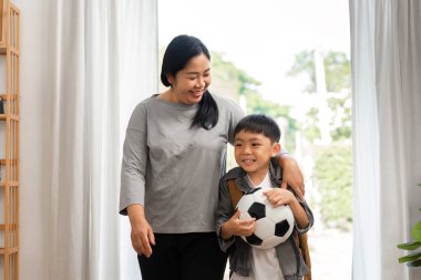 Bir anne ve oğlu futbol antrenmanından sonra birlikte yürürler, gülüşürler ve kahkahalar atarlar, aile bağlarını vurgularlar..