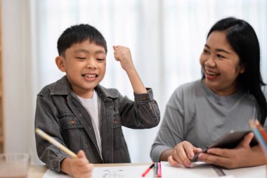 Genç bir çocuk, bir okul ödevini tamamladıktan sonra başarısını kutlar. Annesinin sevincini paylaşarak cesaretlendirmenin önemini vurgular..