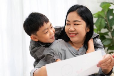 Bir anne ve oğlu birlikte yaratıcı bir anın tadını çıkarırlar. Çocuk çizimlerini gösterirken, sıcak evlerinde kahkahalarını ve sıcaklığını paylaşırlar..