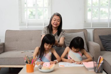 Bir büyükanne, sanatını icra ederken torunlarıyla sevgi dolu bir şekilde ilişki kurar ve evde yaratıcı ve destekleyici bir ortam oluşturur..