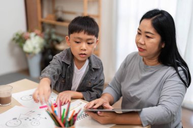 Bir anne, öğrenme teknolojisinin önemini vurgulayarak, bir tablette eğitim içeriğini keşfederken oğluna rehberlik eder..