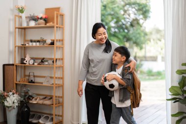 Bir anne ve oğlu okula gitmeden önce neşeli bir anı paylaşıyor, çocuk yaşamında aile bağlarının ve desteğin önemini vurguluyorlar..