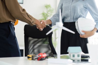 İki profesyonel arasındaki bir tokalaşma, sürdürülebilir konut projelerinde ortaklığı simgeleyerek, işbirliği ve çevre dostu çözümlere bağlılığı vurguladı.