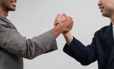 İki erkek el sıkışıyor, iş bağlamında başarılı bir işbirliği ya da anlaşmaya işaret ediyor, profesyonellik ve karşılıklı saygı gösteriyor.