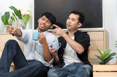 Birbirini seven bir çift, rahatça otururken kahkahalarını ve sohbetlerini paylaşmaktan zevk alır. Bağlantıları, LGBT ilişkilerinin güzelliğini gösteren samimiyet ve sıcaklığı yansıtır..