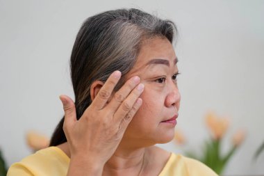 Olgun bir kadın güzellik rutinini yapar. Aynada yansımasını kontrol eder. Cilt bakımı yapar..