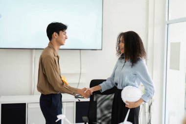 Bir erkek ve kadın el sıkışıyor, sürdürülebilir bir girişim üzerine olan anlaşmalarını sonuçlandırıyorlar, kendi alanlarında profesyonellik ve işbirliği sergiliyorlar..