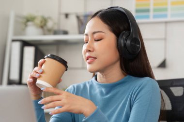 Sıcak bir ofis ortamında, bir kadın kahvesini yudumlarken tasarım işini düşünür, yaratıcılığın ikiliğini yakalar ve düşünceli bir şekilde düşünür..