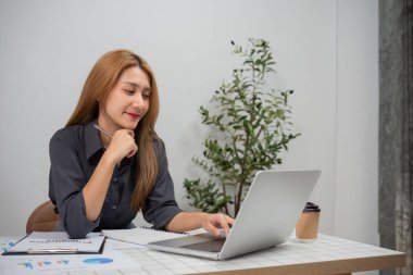 İş kadını bilgisayarındaki grafikleri analiz etmeye odaklanmış, modern ofis çalışmaları ve finansal analizler sergiliyor.