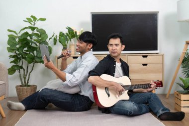 Bir çift eğlenceli bir karaoke seansına katılıyor. Biri gitar çalarken diğeri şarkı söylüyor. Neşe ve müzik bağlarını vurguluyor..