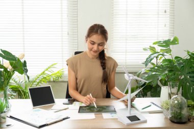 Yaratıcı bir kadın tabletinde sürdürülebilir tasarımlar yaratmaya odaklanarak çevresel sorumluluğa olan bağlılığını vurguladı..