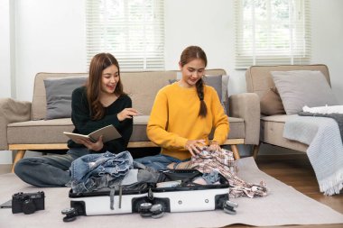 İki genç kadın, kıyafetlerini bavula koyup, heyecanlı yolculuklarına hazırlanırken kahkahalar ve sohbetler ediyorlar..