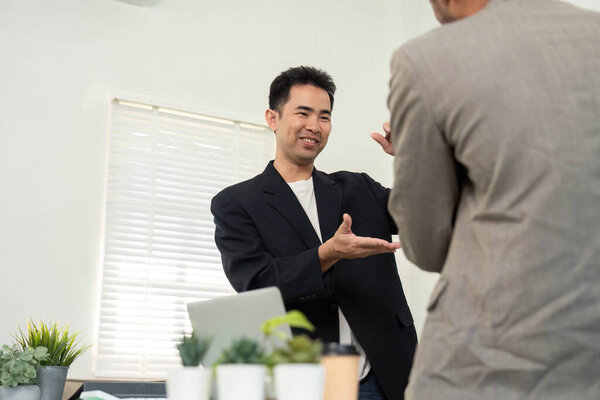 В современном офисе два профессионала эффективно общаются, обсуждая стратегии и идеи для своего проекта, подчеркивая командную работу..