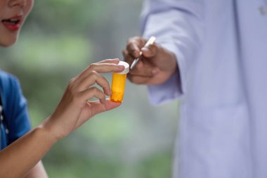 Hastaya reçeteli ilaç şişesini teslim eden bir doktor net iletişim ve sağlık hizmetlerine olan güvenin önemini vurguladı..