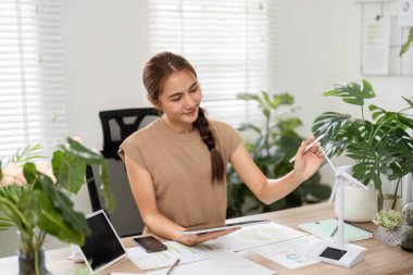 Bir kadın yeşil ofisteki verileri analiz eder, tableti ve düşünceli ifadesiyle ESG sürdürülebilirlik çabalarına odaklanır..
