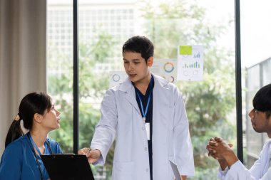 İş arkadaşlarıyla hasta bakımı, daha iyi sağlık hizmetleri sonuçları hakkında görüşler ve stratejiler paylaşan bir doktor.