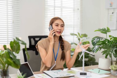 Bitkiler ve sürdürülebilirlik projeleriyle dolu parlak bir ofiste tutkulu bir şekilde çevre dostu fikirler sunan genç bir kadın..
