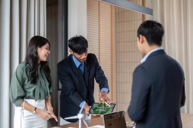 Teknoloji ve yenilenebilir modellerle çevrili bir sürdürülebilirlik toplantısında ESG ile ilgili görüşleri paylaşan iki profesyonel modern bir çalışma alanında.
