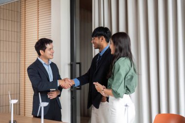 Profesyoneller takım çalışması yapar ve ESG sürdürülebilirlik çabalarını ofis ortamında el sıkışarak kutlarlar..