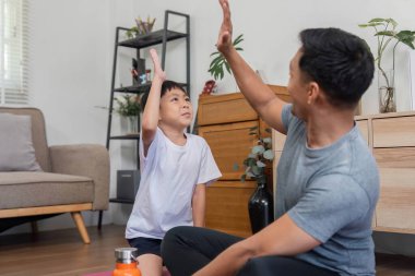 Evde eğlenceli egzersiz aktivitelerine katılan bir baba ve oğul kaliteli zaman geçirir ve aile bağlarını güçlendirir..