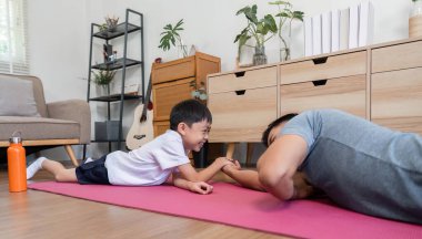 Neşeli bir baba ve oğul evde hafif bir bilek güreşinin keyfini çıkarıyorlar, bağlarını güçlendiriyorlar ve fitness 'i eğlenceli hale getiriyorlar..