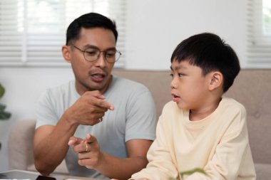 Evde eğitim veren bir baba, oğluna etkileşimli aktiviteler yoluyla matematik kavramları öğretiyor, öğrenim ortamını geliştiriyor..