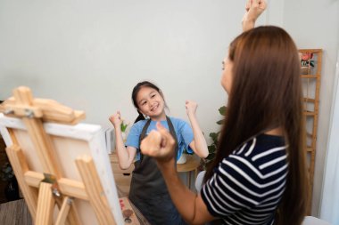 Bir kız, yaratıcılığını aile zamanı boyunca neşeli ifadelerle kutlar. Bir sanat stüdyosunda annesiyle coşkuyu paylaşır..