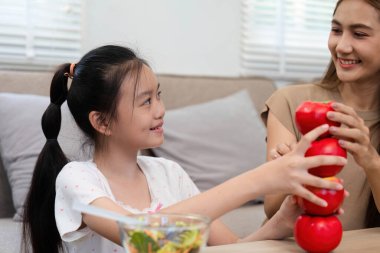 Bir anne ve kız, evde sağlıklı beslenmeyi ve sağlıklı beslenmeyi teşvik etmek için elmaları eğlenceli bir aktivite olarak istiflemekten hoşlanırlar..