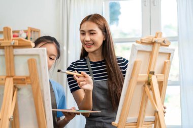 Resim yaparken kızına rehberlik eden bir anne yaratıcı enerjiyle dolu bir çevrede teknikler ve neşe paylaşıyor..