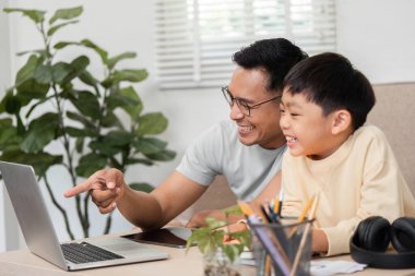Bir baba ve oğul, bir dizüstü bilgisayarda birlikte eğitici içeriği keşfederek, bağlarını güçlendirerek keyifli bir ev okulu anlarını paylaşıyorlar..