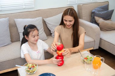 Yaratıcı bir anne ve kız evdeki sağlık ve sağlıklı alışkanlıkları vurgulamak için elmalarla eğlenceli bir istifleme aktivitesine girişiyor..