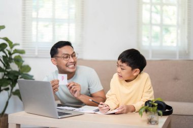 Neşeli bir baba oğluna eğlenceli aktivite kartları göstererek, öğrenmeyi interaktif hale getiriyor..