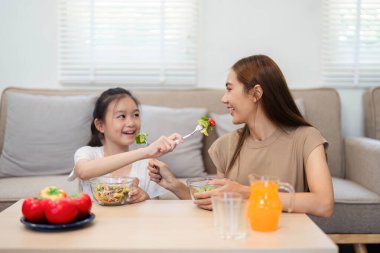Bir anne ve kızın sağlıklı salataları paylaşması, sağlıklı beslenmenin ve aile bağlarının önemini gösteriyor..