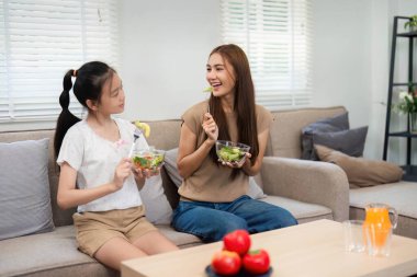 Bir anne ve kız olarak neşeli bir etkileşim sağlıklı yiyecekleri paylaşır, canlı bir ev ortamında sıcaklık ve neşe iletir..