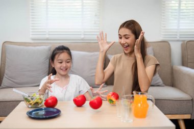 Bir anne ve kızın elma ve salatayla heyecanlarını ifade ettiği, neşe ve sağlıklı alışkanlıkları beslediği eğlenceli ve eğlenceli bir an..