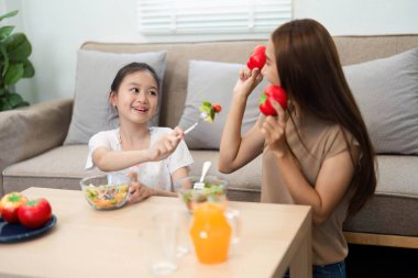 Bir anne ve kızı arasında eğlenceli bir etkileşim, sağlıklı beslenmeye olan sevgilerini evde taze sebzelerle göstermeleri, sağlıklı olmayı teşvik etmeleri..
