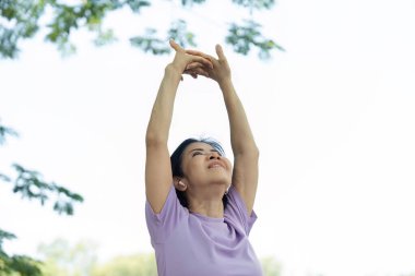 Bir kadın açık havada neşeli bir şekilde esniyor. Parlak ve açık bir ortamda refahı ve pozitifliği kucaklıyor..