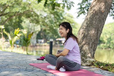 Neşeli bir kadın yoga minderinde bir anlık mutluluktan zevk alır, doğadaki refahı ve pozitifliği somutlaştırır..