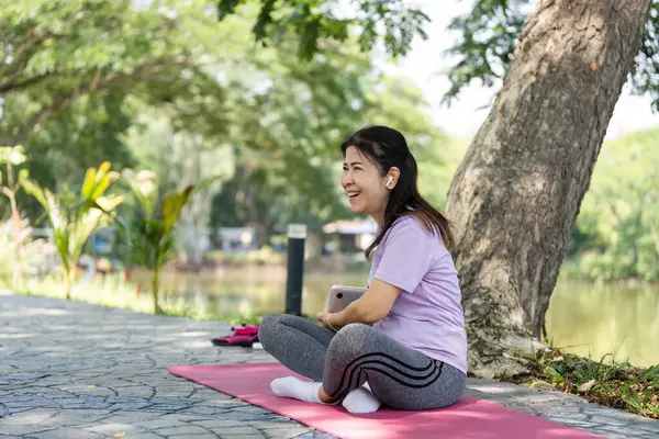 Neşeli bir kadın yoga minderinde bir anlık mutluluktan zevk alır, doğadaki refahı ve pozitifliği somutlaştırır..